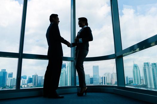 Asian business people handshake to seal deal in front of city skyline