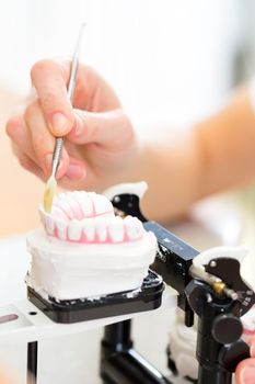 Female dental technician or orthodontist producing denture with imprint