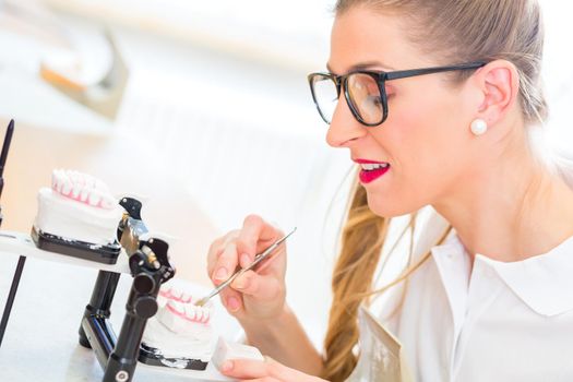 Female dental technician or orthodontist producing denture with imprint