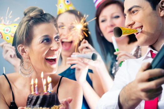 Party people in bar celebrating birthday with cake