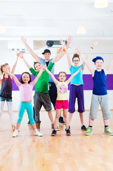 Dance teacher giving children Zumba fitness class in gym