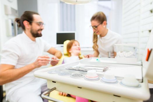 Dentist giving girl treatment in dental surgery