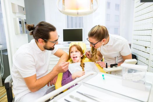 Dentist giving girl treatment in dental surgery