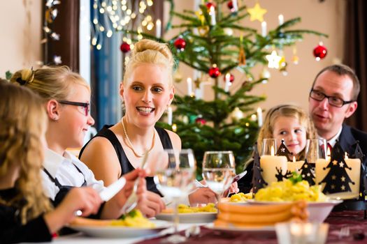 Family of Mother, father, children celebrating Christmas eve with traditional dinner Wiener sausages and potato salad