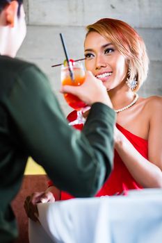 Asian couple drinking cocktails in fancy bar