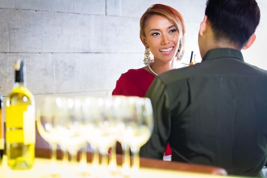 Asian couple drinking white wine in fancy bar