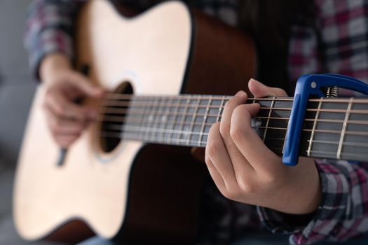 Woman's hands playing classic acoustic guitar with capo, close up