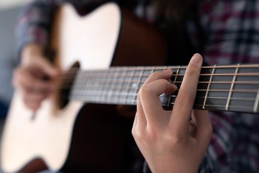 Woman's hands playing classic acoustic guitar, close up