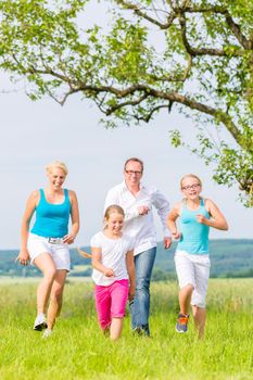 Family, Parents and daughters run over field or lawn in summer