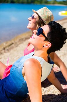 Women relaxing at lake beach in summer sun