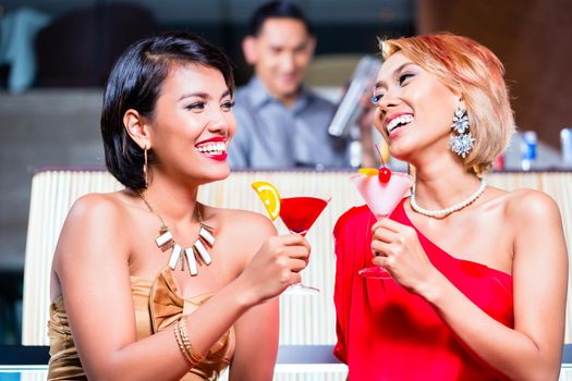 Asian women drinking cocktails in fancy bar