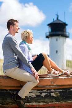 Couple having romantic vacation in German north sea beach dune in front of lighthouse