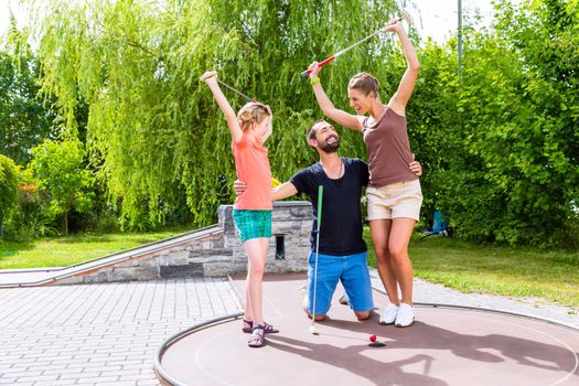 Family playing miniature golf outdoors