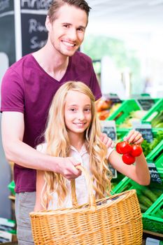 Father and daughter selecting vegetables while grocery shopping in organic supermarket