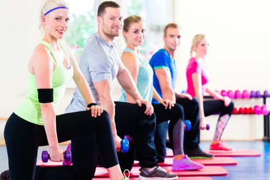 fitness people in gym working out with dumbbells