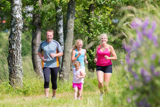 Parents with children sport running together through forest