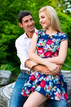 Man and woman embracing in summer park looking at each other being a couple