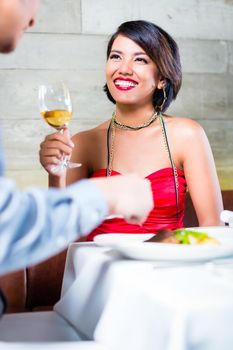 Asian couple having dinner and drinking red wine in very fancy bar or restaurant