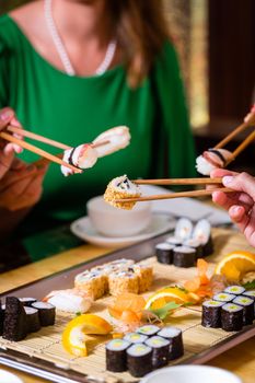 Young people eating sushi in Asian restaurant