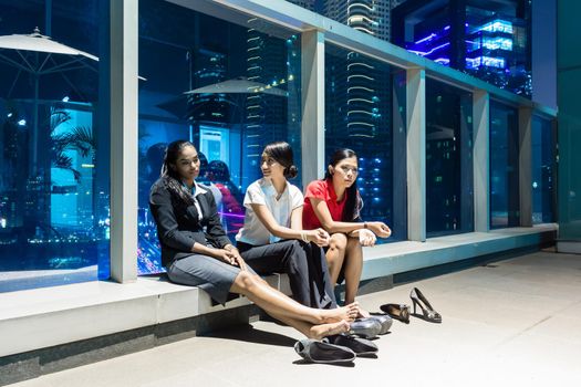 Overworked business people after hour resting in front of nightly city skyline