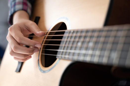Woman's hands playing classic acoustic guitar, close up