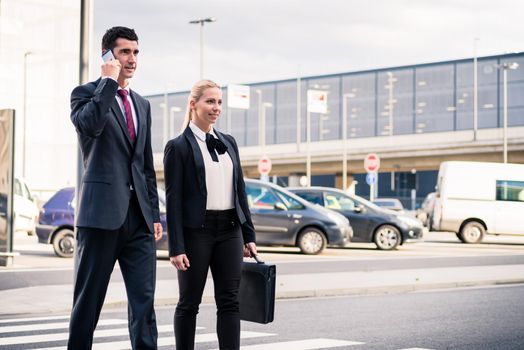 Business people at airport terminal travelling wearing briefcase and talking to smart phone