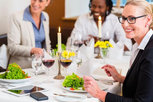 Team of business people eating in restaurant, food and wine on the table