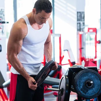 Man taking weights from stand in fitness gym preparing for training
