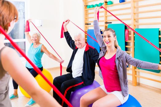 Senior people at fitness course in gym exercising with stretch band