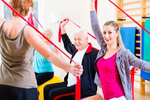 Senior people at fitness course in gym exercising with stretch band