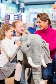 family in toy store cuddling with stuffed animal, mother with two daughters