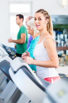 Group with senior and young men and women on treadmill in fitness gym running for sport