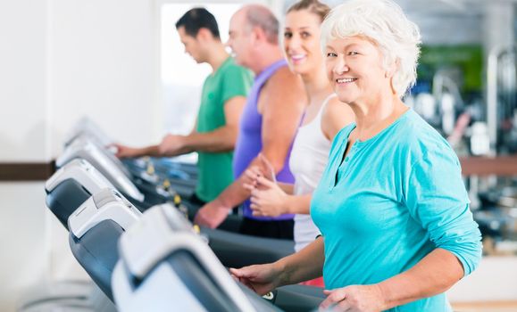 Group with senior and young men and women people on treadmill in fitness gym running for sport