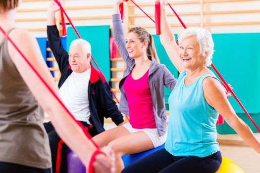 Senior people at fitness course in gym exercising with stretch band