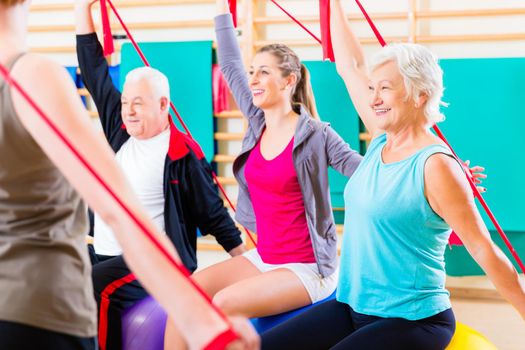 Senior people at fitness course in gym exercising with stretch band