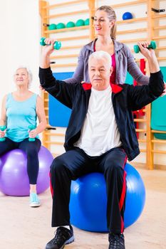 Physiotherapist coaching senior people exercising with dumbbells