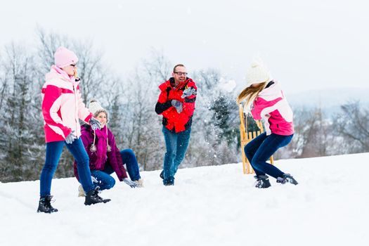 Family with kids having snowball fight in winter