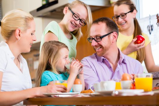 Family in their home having breakfast with eggs, fruit, coffee and juice