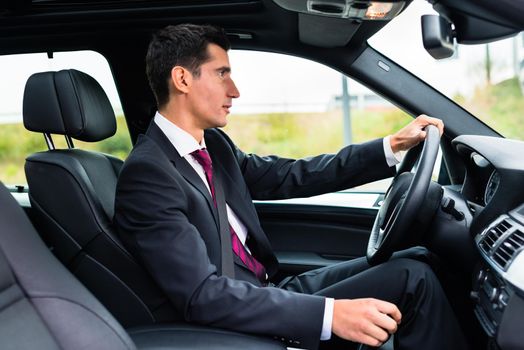 Man driving his car for business travel wearing a suit