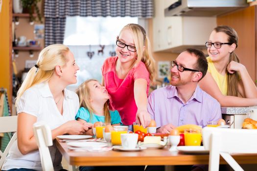 Family having joint breakfast in kitchen eating and drinking