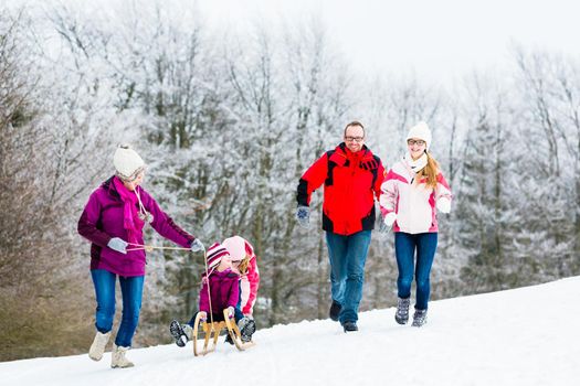 Family with kids having winter walk in snow