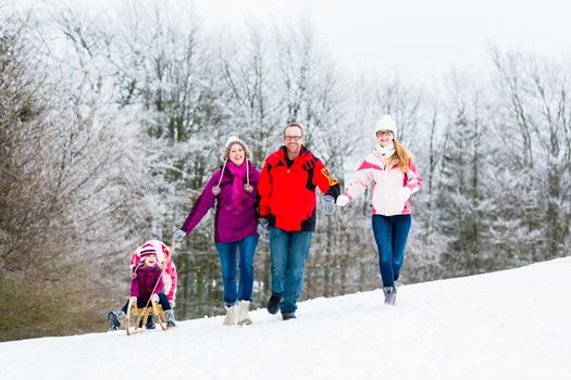 Family with kids having winter walk in snow