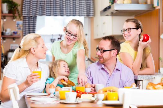 Family having joint breakfast in kitchen eating and drinking