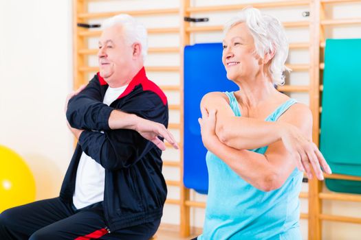 Senior people in fitness exercise doing gymnastic stretching