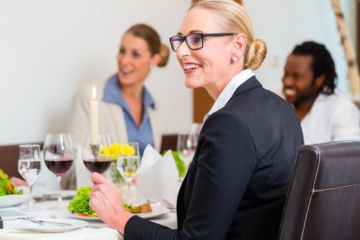 Team of business people eating in restaurant, food and wine on the table