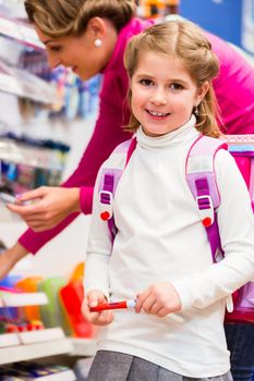 Family buying school supplies in stationery store, little girl looking at a fountain pen