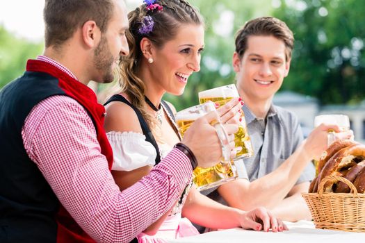 People with beer and pretzel in Bavarian inn eating and drinking