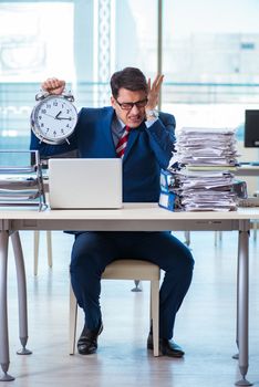 Businessman employee in urgency and deadline concept with alarm clock