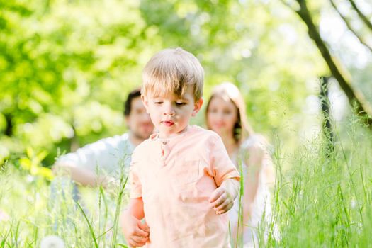 Boy running and playing on meadow with the family