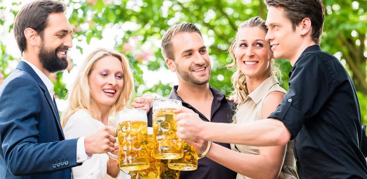 Friends or colleagues on beer garden after work toasting with drinks